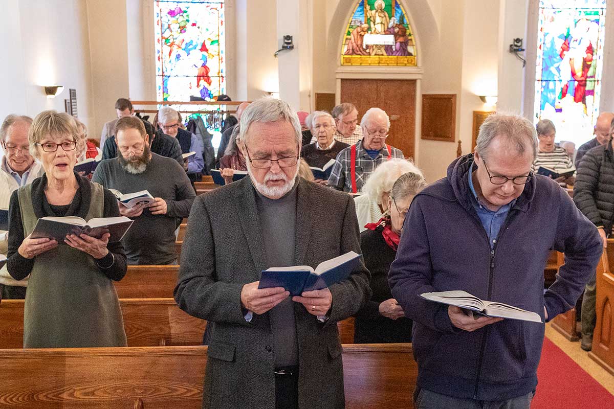 Large group of people in a church singing from a Hymn Book