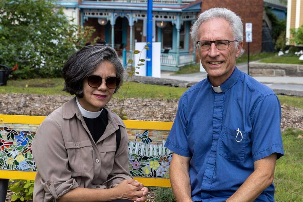 Two people posing for the camera on a bench